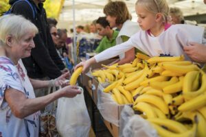 Fiatal önkéntes banánt ad át egy idős hölgynek jótékonysági ételosztáson – érzelmekkel teli dokumentarista eseményfotózás a FotoFilo vizuális krónikájában