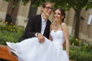 Vidám ifjú pár, a vőlegény ölében tartja a menyasszonyt egy szabadtéri esküvői helyszínen – professzionális esküvői eseményfotózás és pillanatképek a FotoFilo-tól.